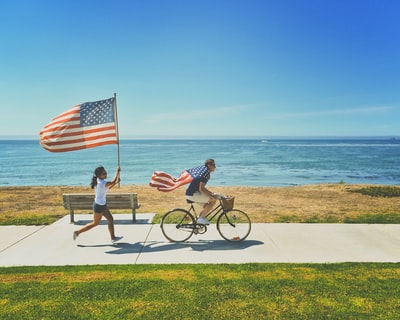 手持美国国旗的男子骑自行车和女子跑步
